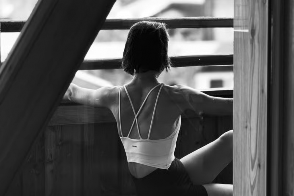 Frau mit Rücken zugewandt sitzend in Yoga-Pose